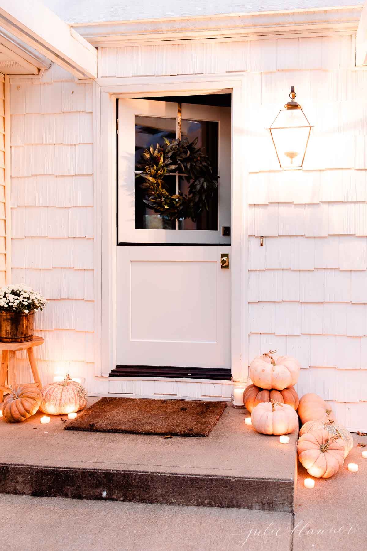 A cottage dutch door, opened on the top half, with candles and pumpkins for fall decor ideas