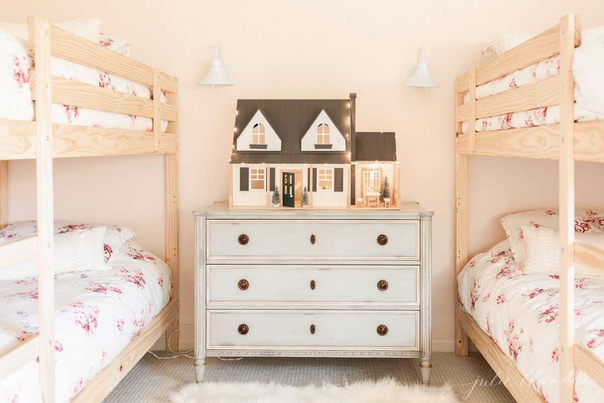 A girl's bedroom in a lake cottage with wooden bunks and a doll house