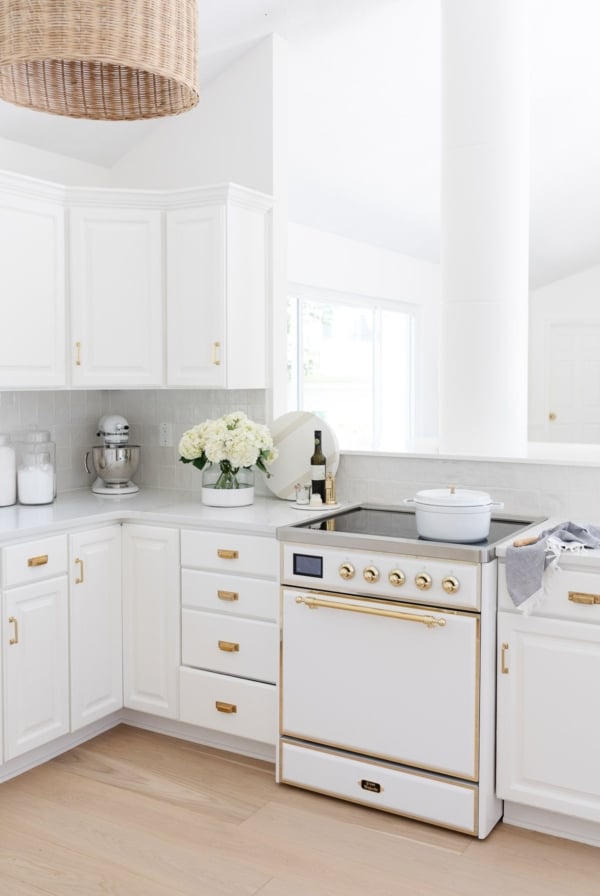 A white kitchen with wood floors, featuring a white ILVE Majestic II range