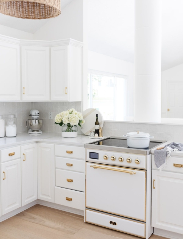 A white kitchen with wood floors, featuring a white ILVE Majestic II range