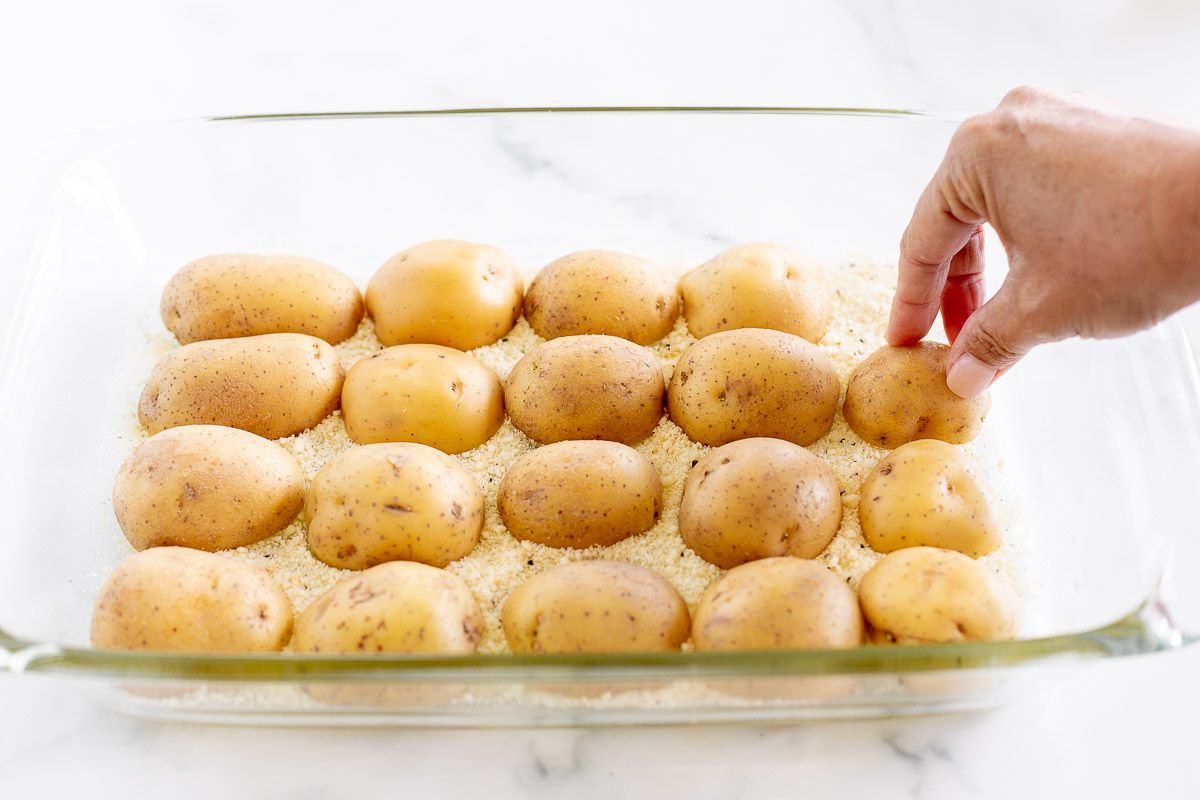 A white baking dish full of parmesan potatoes before baking.