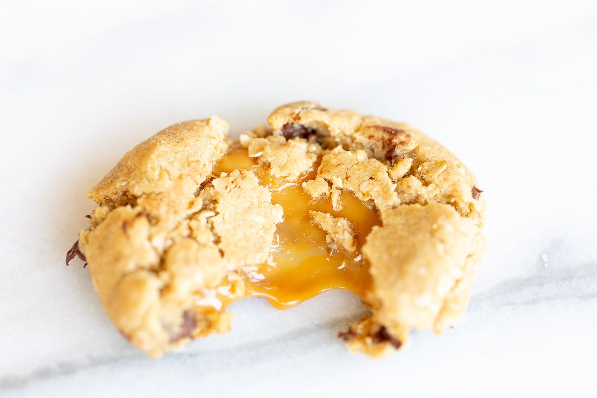 A carmelita cookie torn into two sections, with caramel oozing from the center.