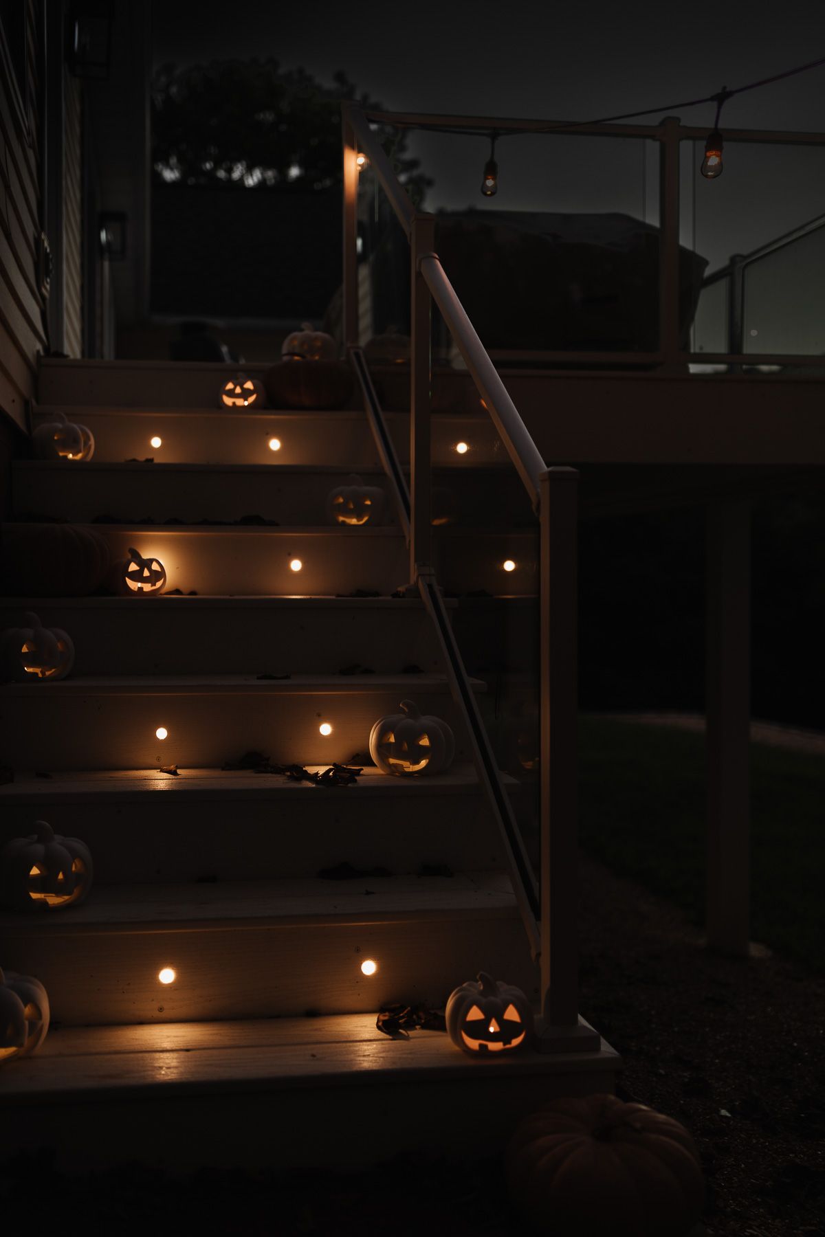 White deck stairs decorated with white glowing jack o lanterns