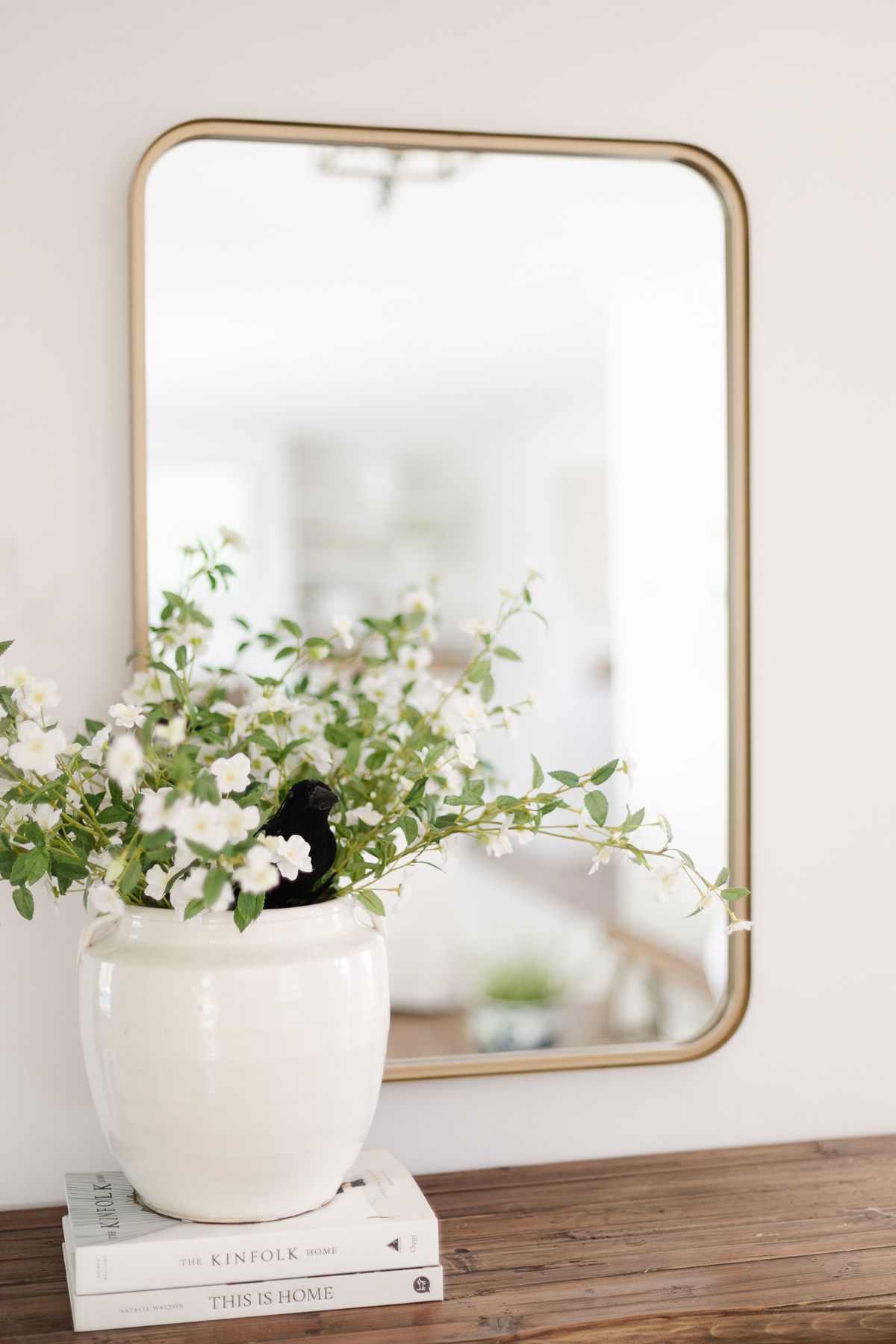 A black crow tucked into a white vase filled with faux white flowers