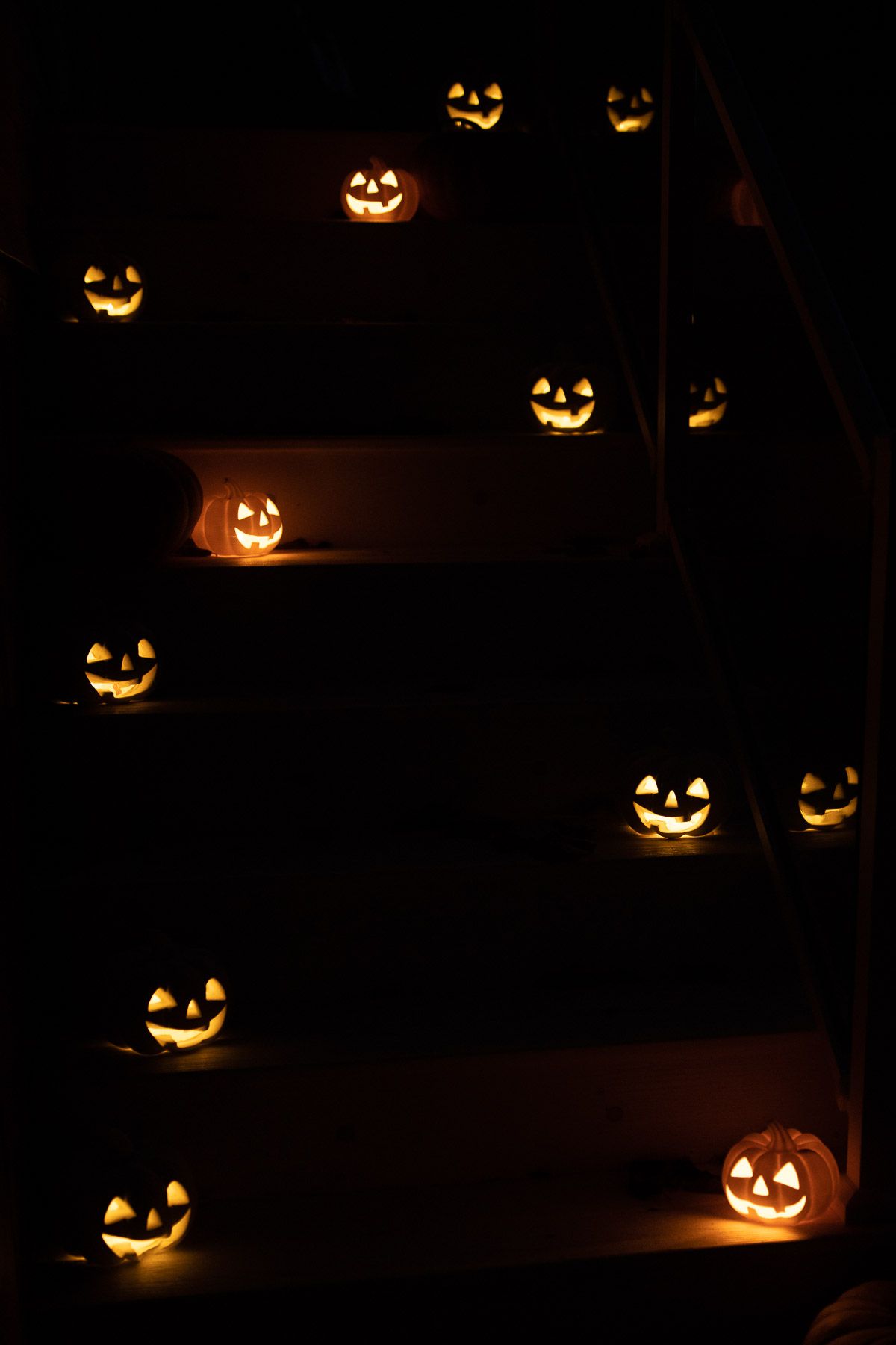 Jack o lanterns glowing on steps, in a dark setting.