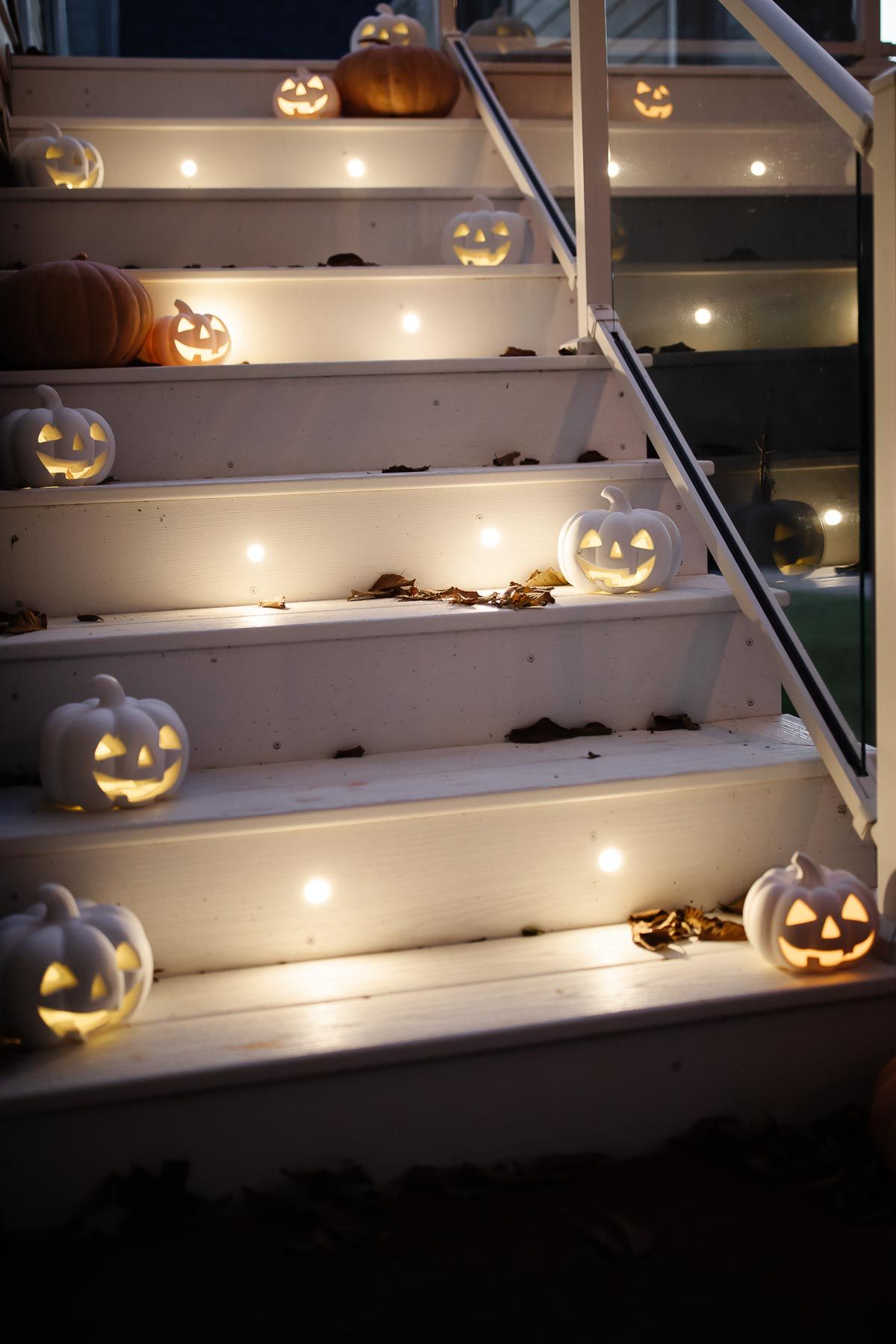 White deck stairs decorated with white glowing jack o lanterns