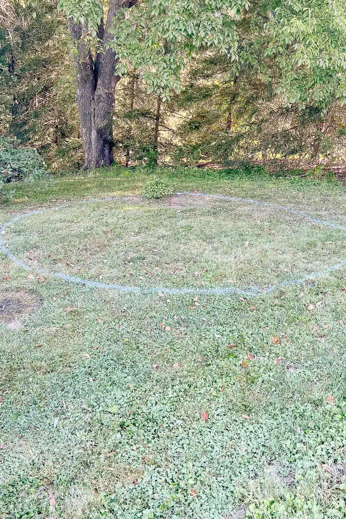 A spray painted circle on a grassy lawn, for a fire pit patio project