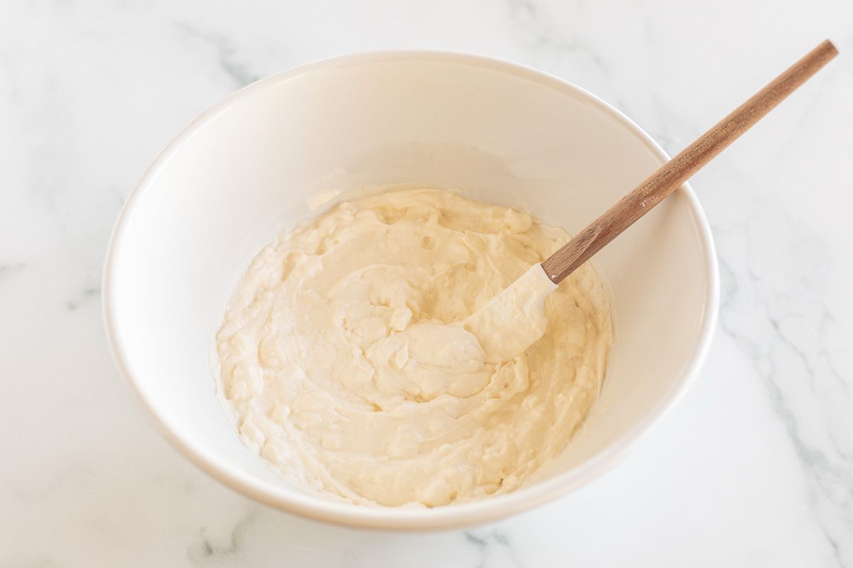 A mixture of cream cheese and more in a white mixing bowl