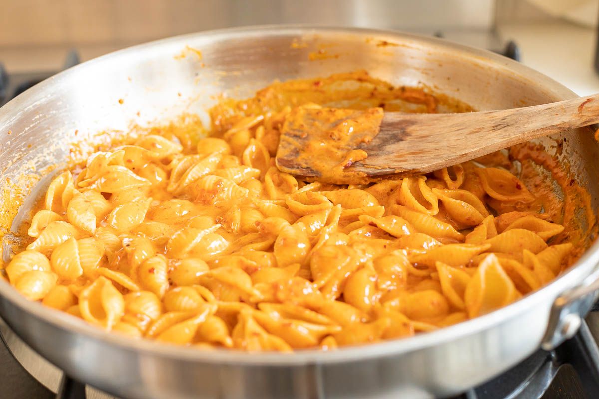 A silver pan full of Gigi Hadid pasta, a spicy vodka shell pasta recipe cooking on a stovetop.