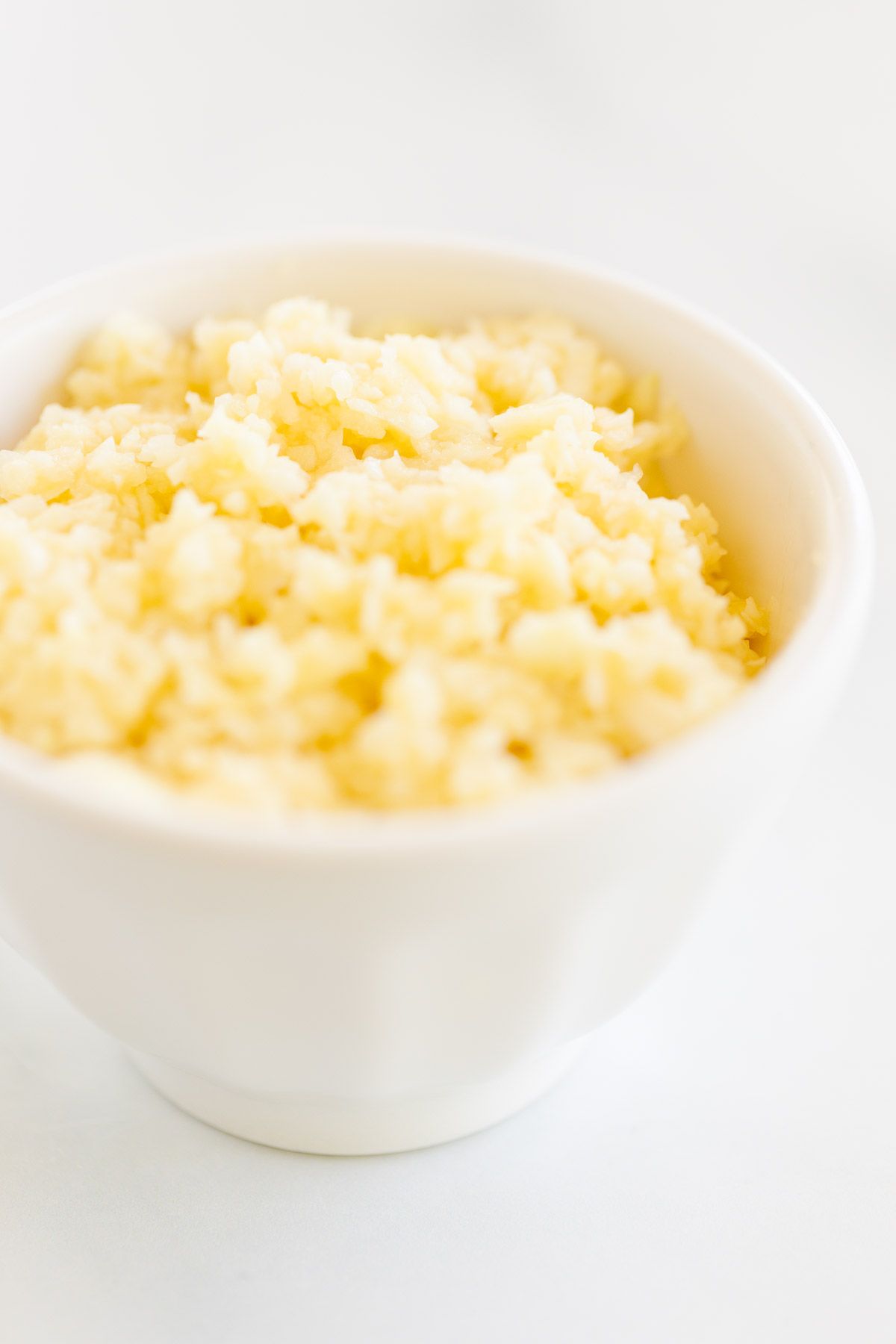 A close up of minced garlic in a white bowl.