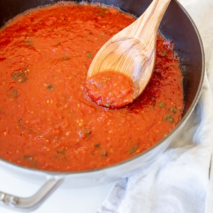 San Marzano Tomato Sauce in a gray cast iron pan, with a wooden spoon.
