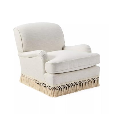 an upholstered armchair with fringe at the base
