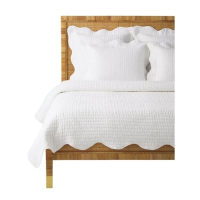 A white bed with scalloped white quilt