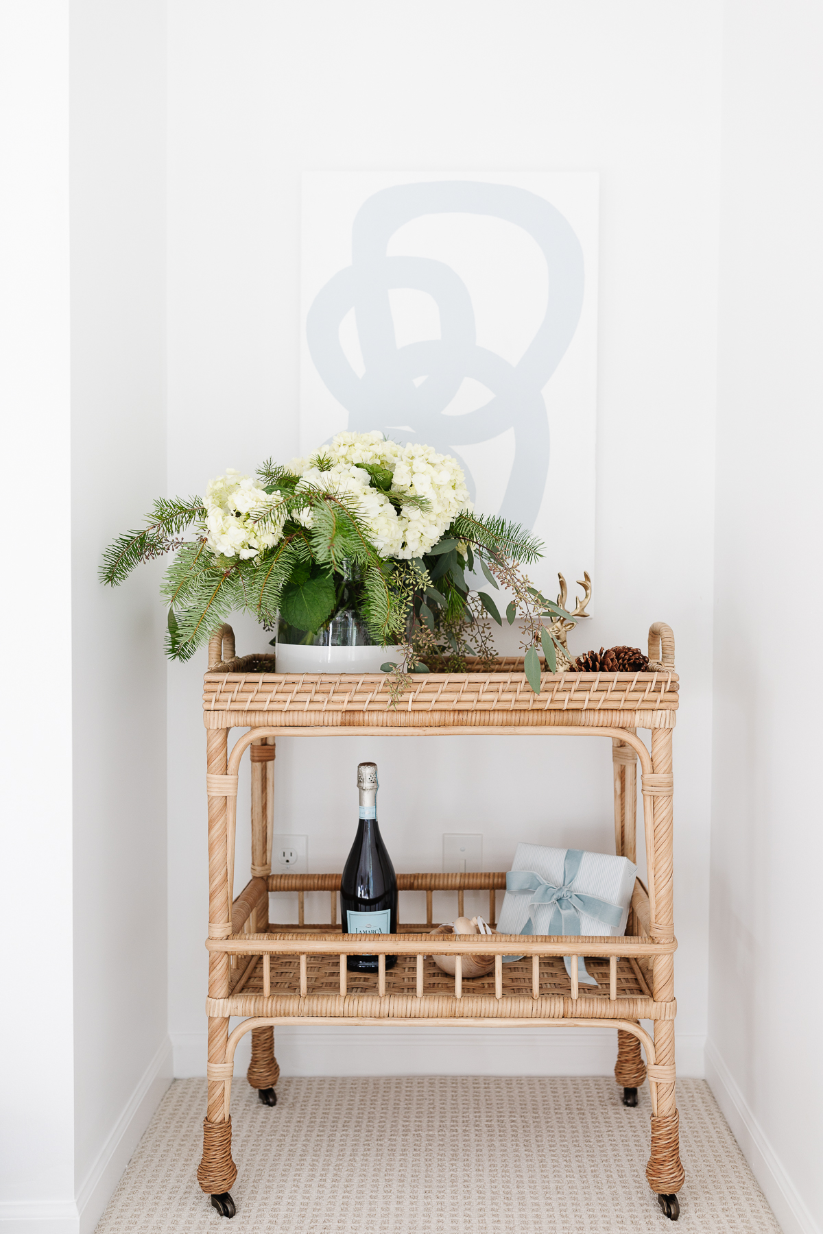 A stylish black Friday wicker bar cart adorned with flowers and a bottle of wine.
