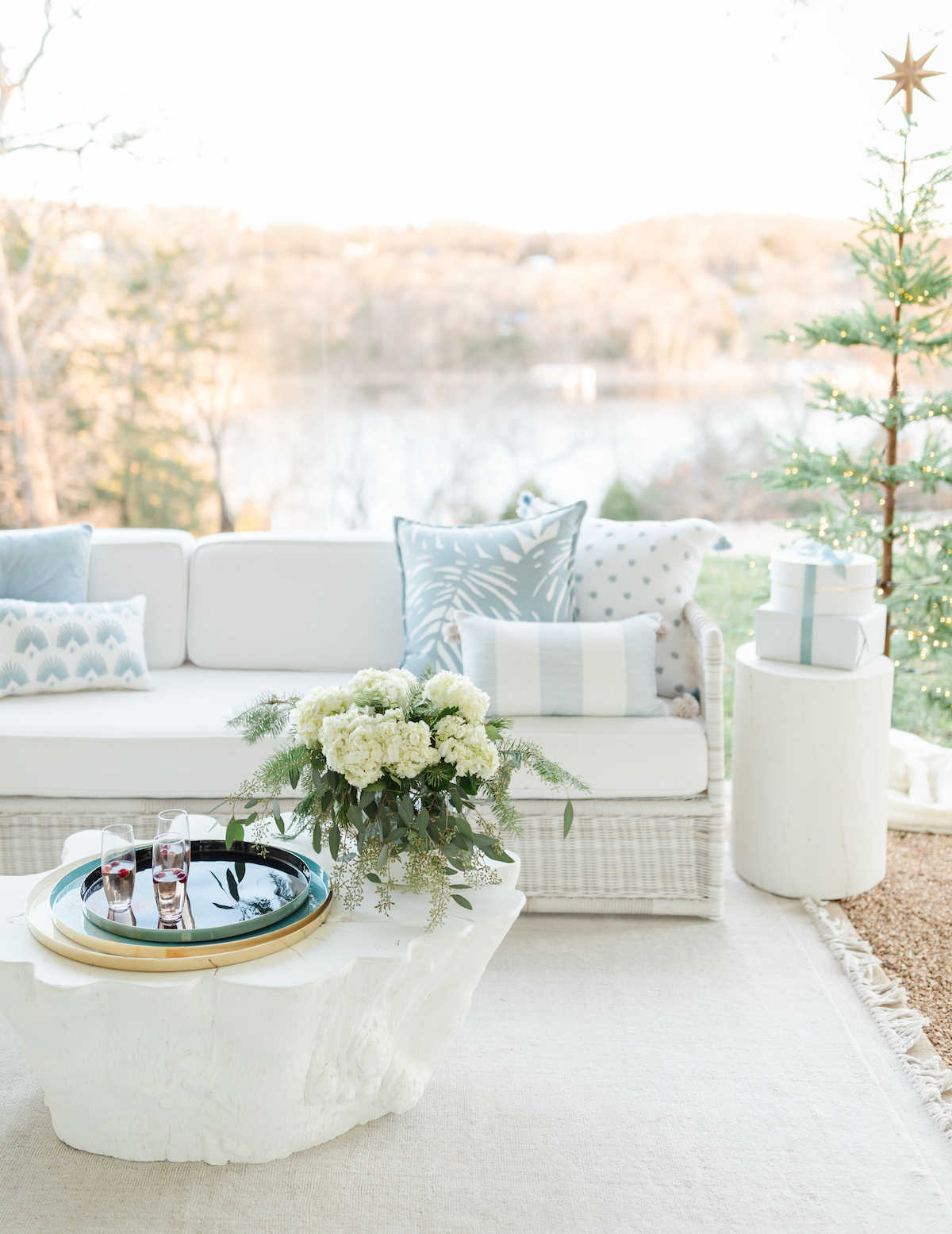 A festive outdoor living room adorned with a beautifully decorated Christmas tree, showcasing a harmonious blend of white and blue hues.