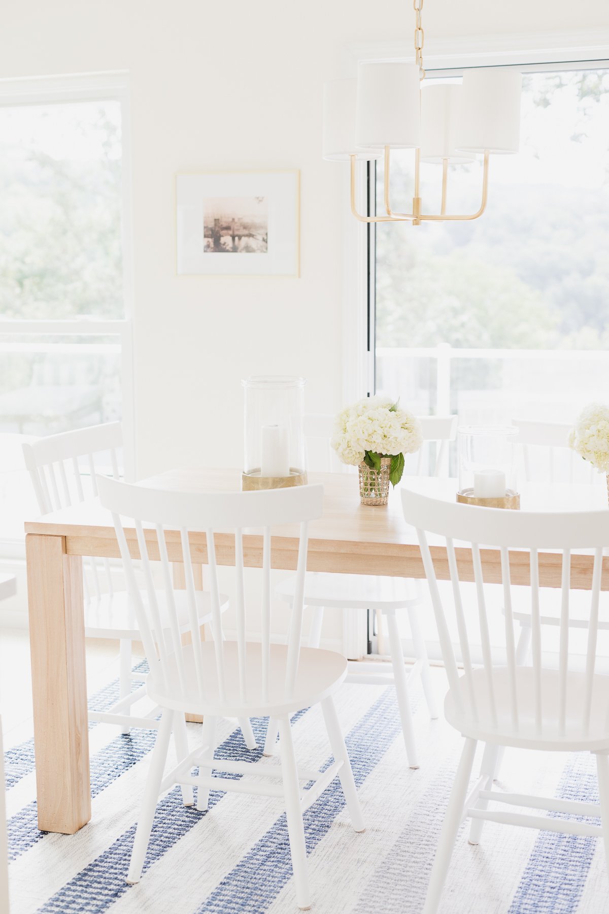 teak kitchen table with white chairs and blue and white stripe rug