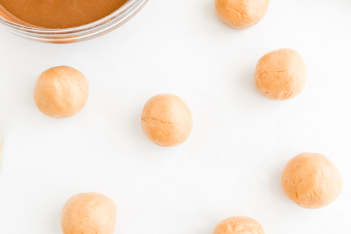 Buckeye recipe - Peanut butter balls on a white surface with a jar of peanut butter.