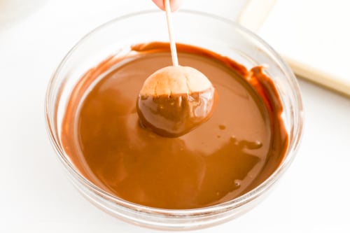 A person is pouring chocolate into a bowl while making a buckeye recipe.
