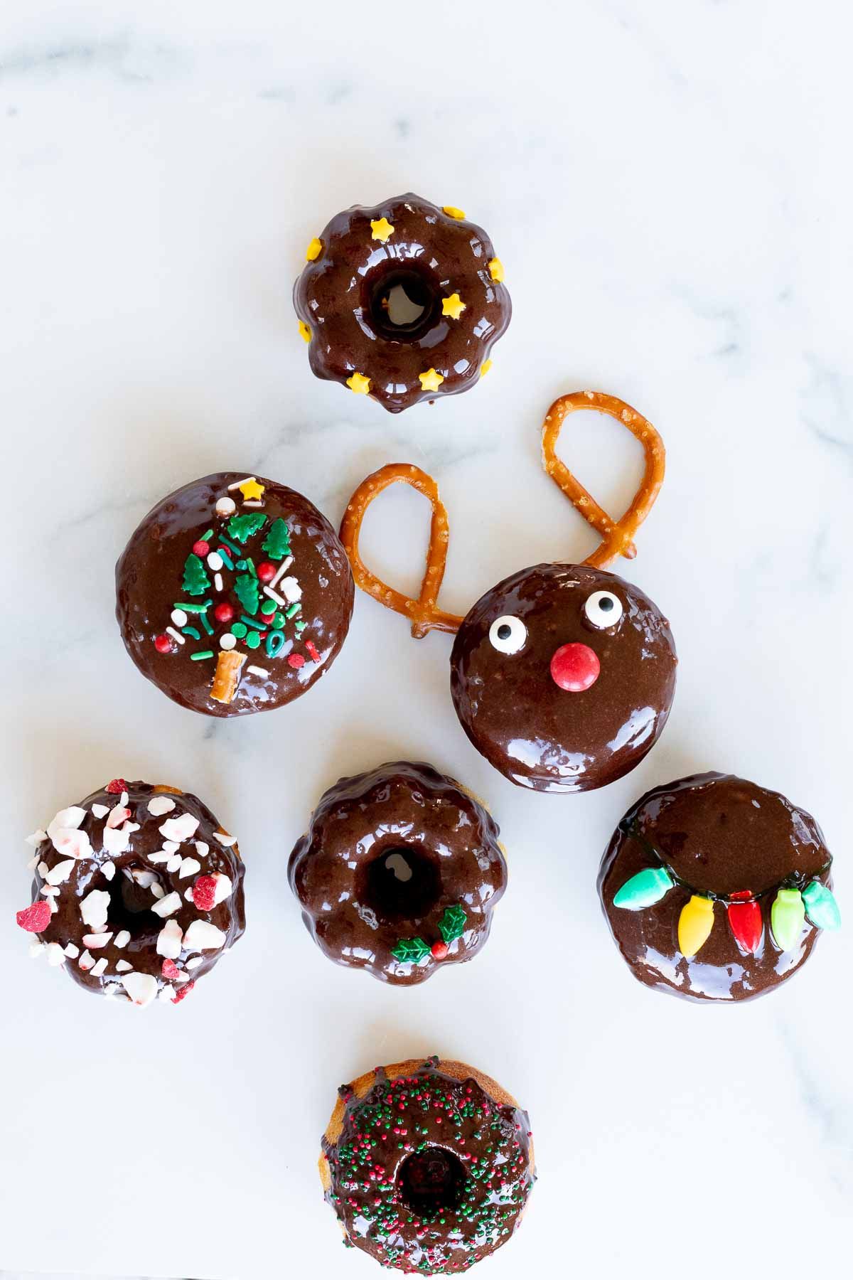 Cute Christmas donuts shaped into a tree, laid out on a white marble countertop.