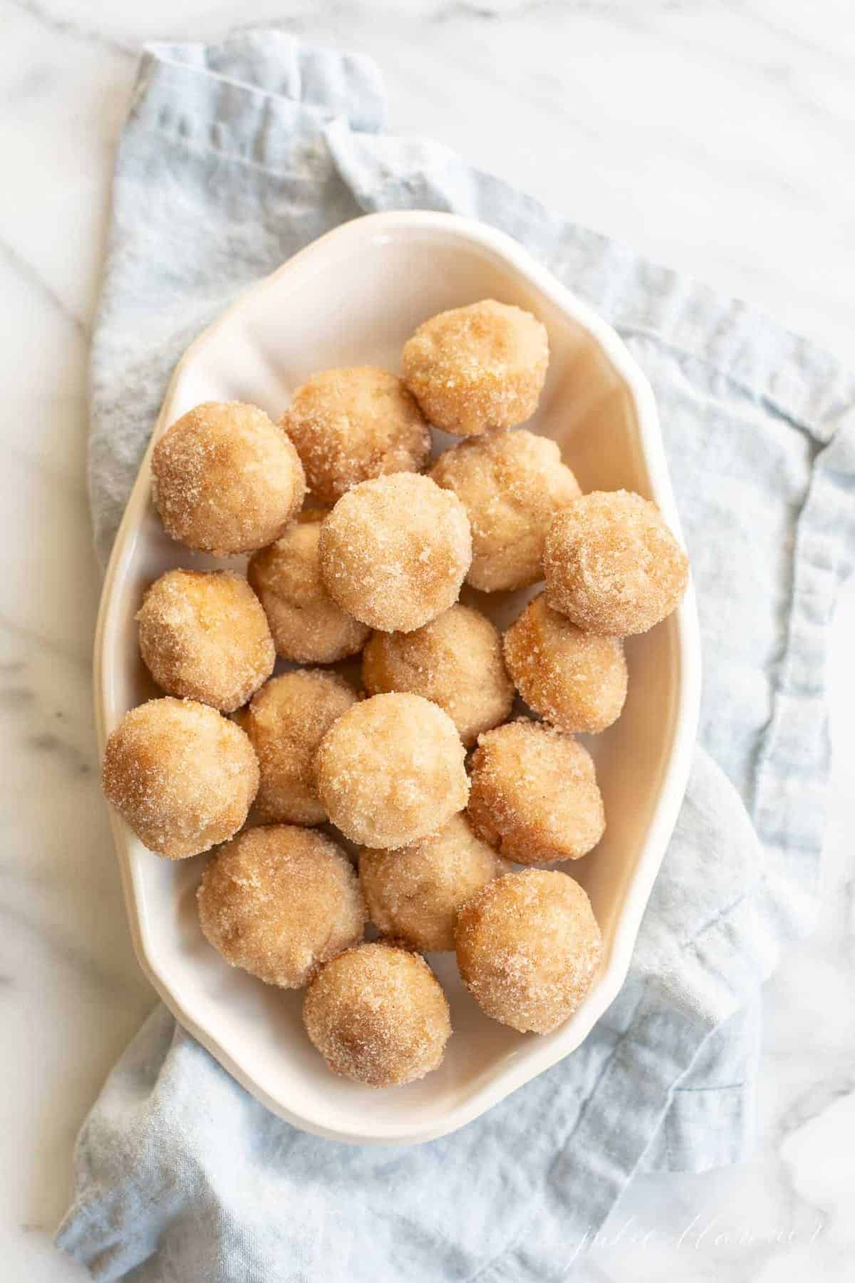 cinnamon meltaway muffins in white serving dish on blue napkin