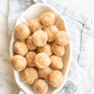 A white oval platter full of mini cinnamon muffins.