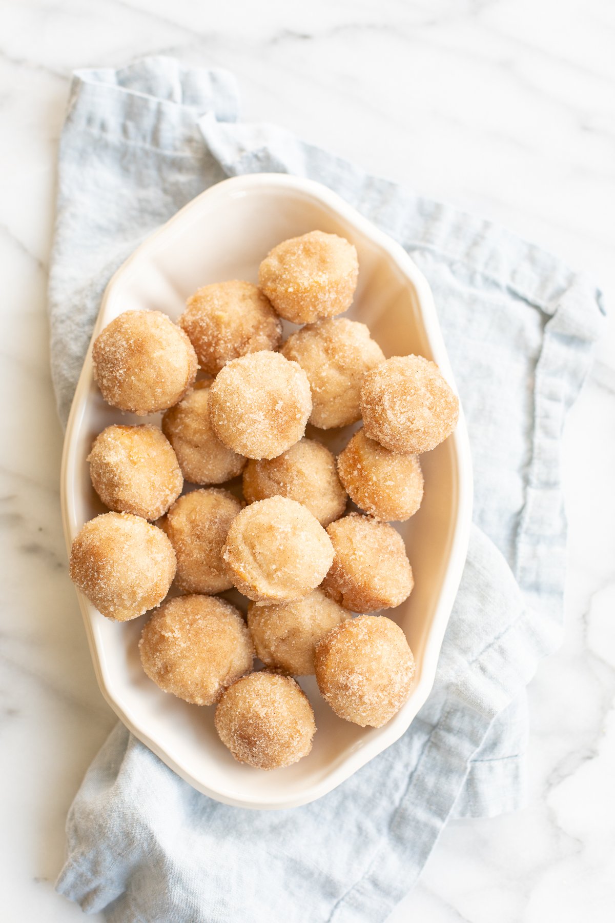 A white oval platter full of mini cinnamon muffins.