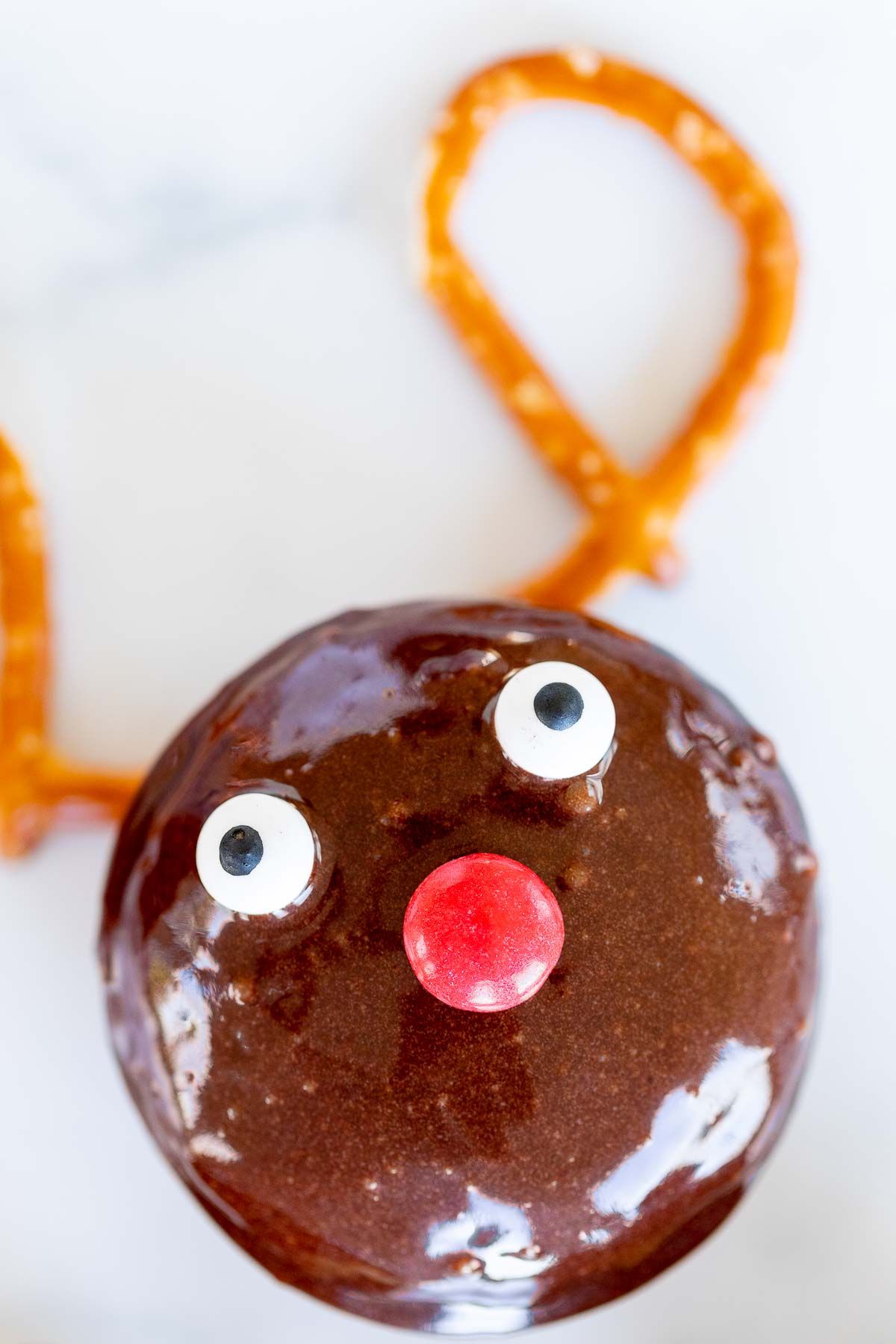 A homemade chocolate reindeer donut on a marble surface.