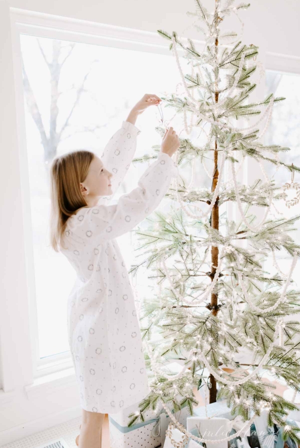 a little girl decorating a sparse christmas tree for a minimalist christmas