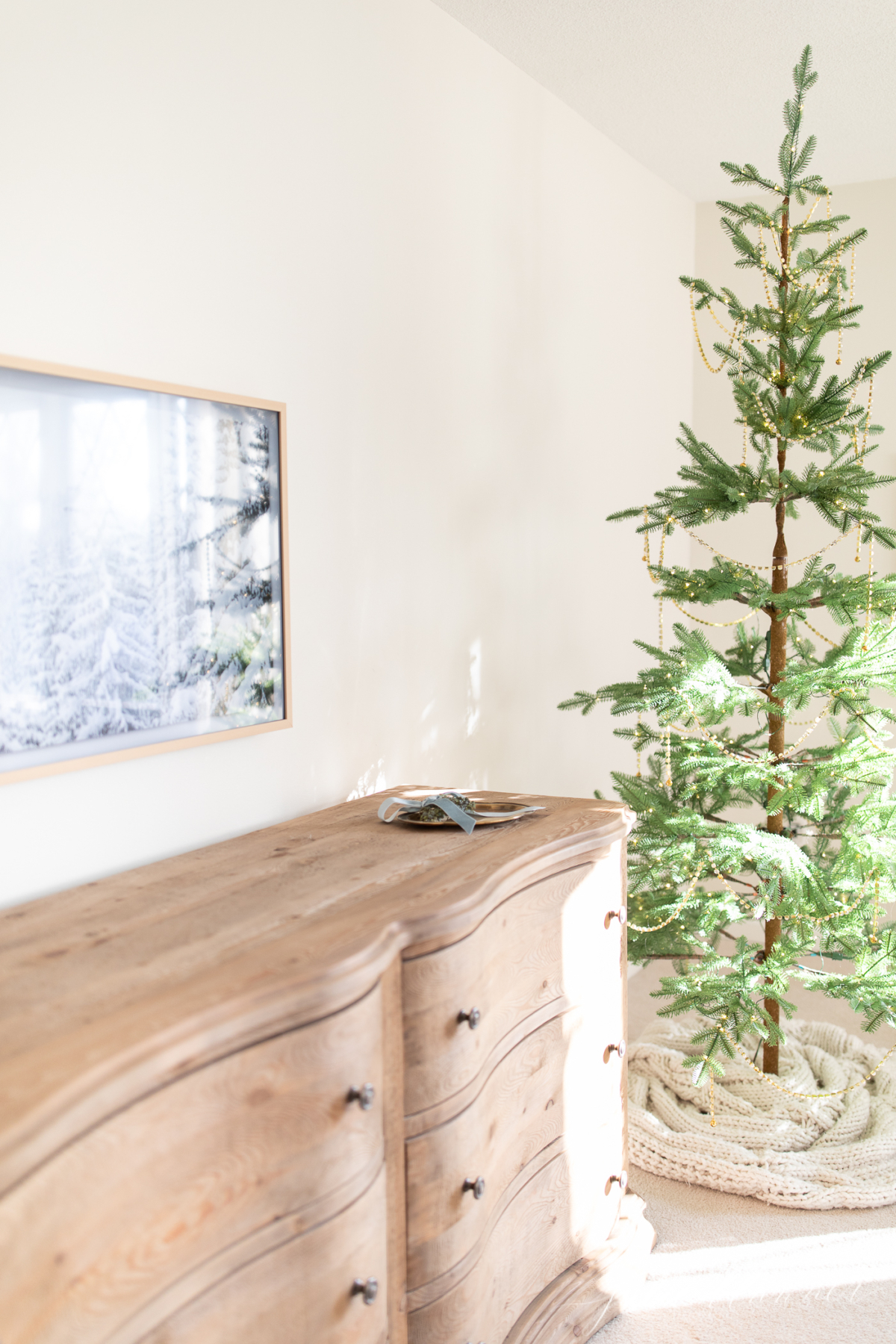 A sparse Christmas tree beautifully displayed in a bedroom.