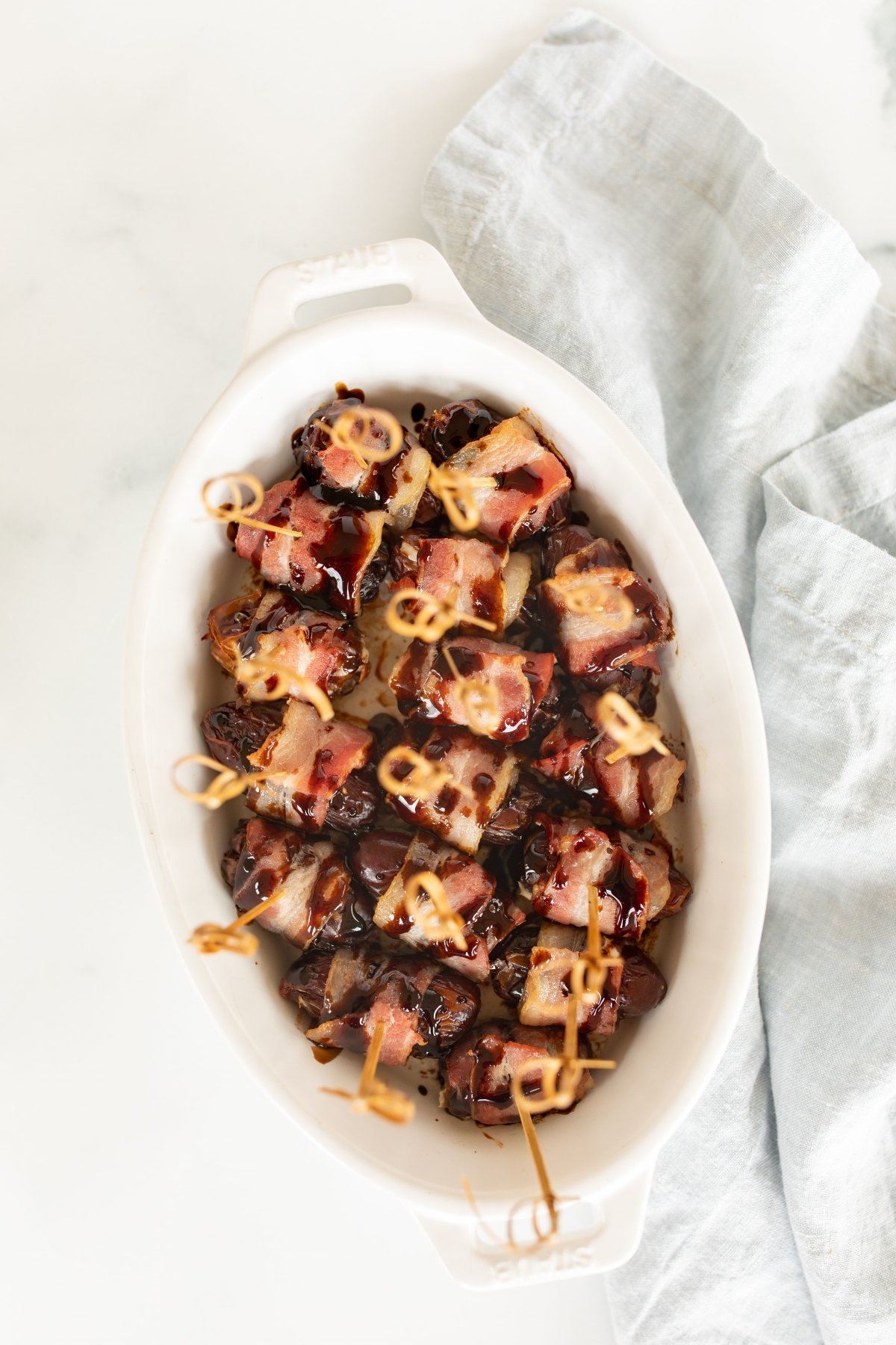 stuffed dates wrapped in bacon in a white dish