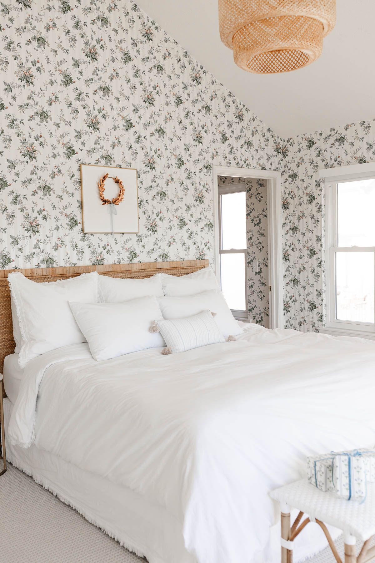 A coastal Christmas bedroom with floral wallpaper and white bedding.