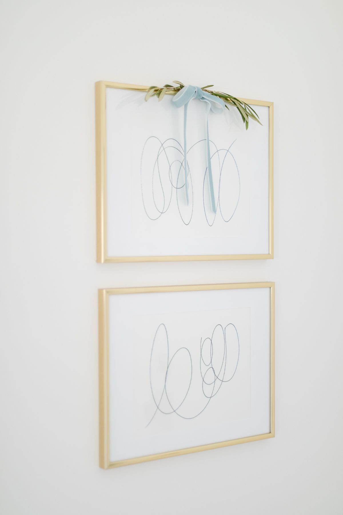 Modern white art in wood frames, accented with a velvet bow and greenery for Christmas.