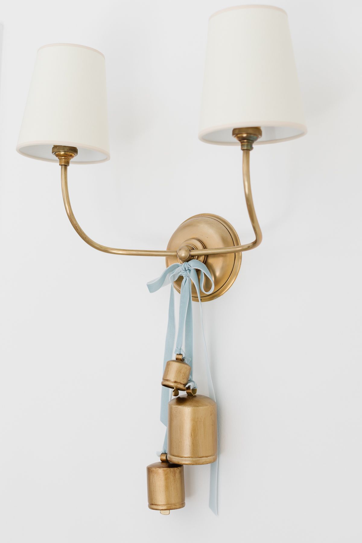 Brass bells tied onto a brass wall sconce with blue velvet ribbon.
