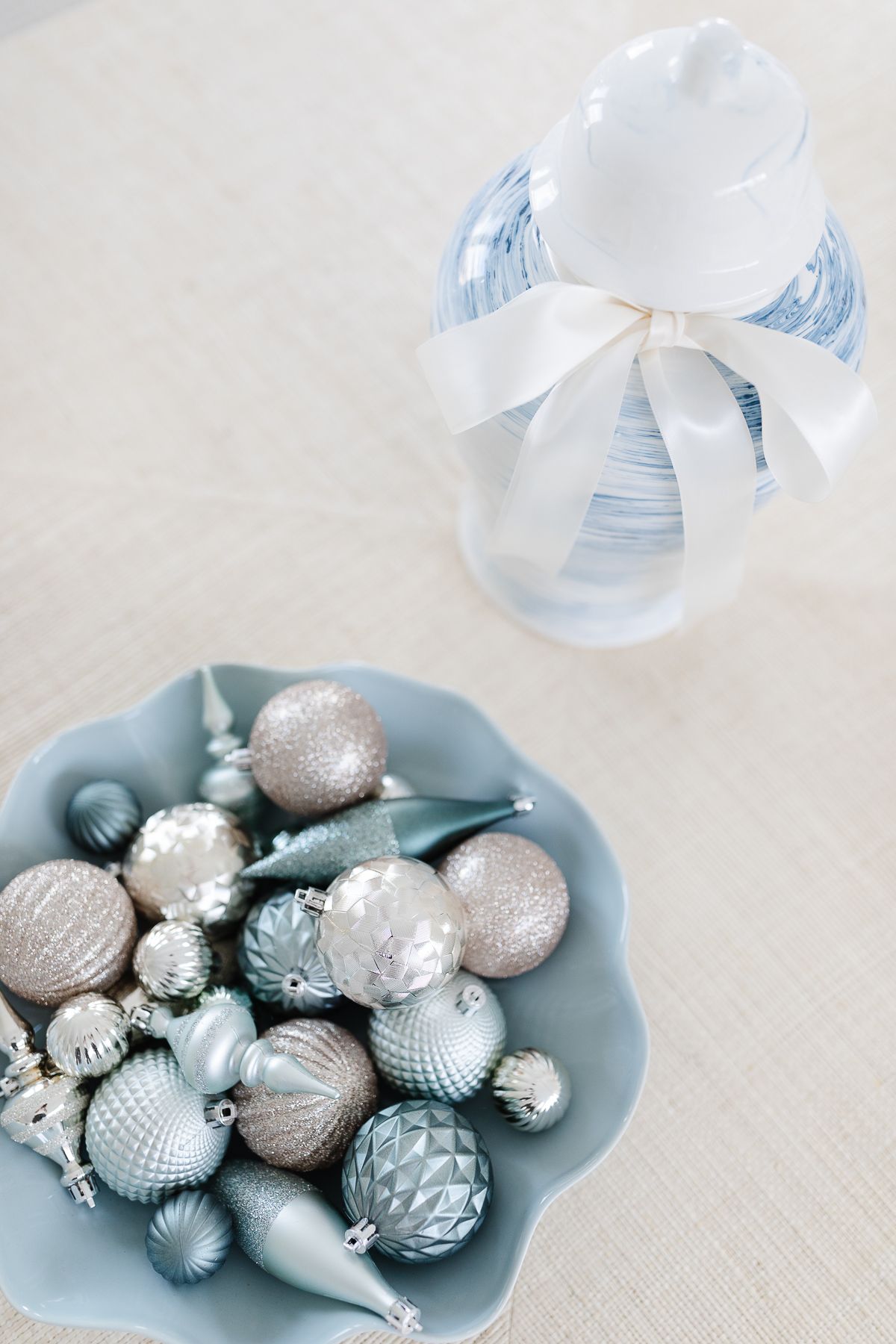 A blue wavy bowl full of pastel ornaments in a coastal Christmas display.