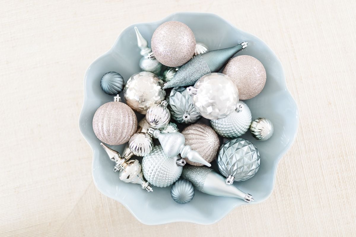 A blue wavy bowl full of pastel ornaments in a coastal Christmas display.