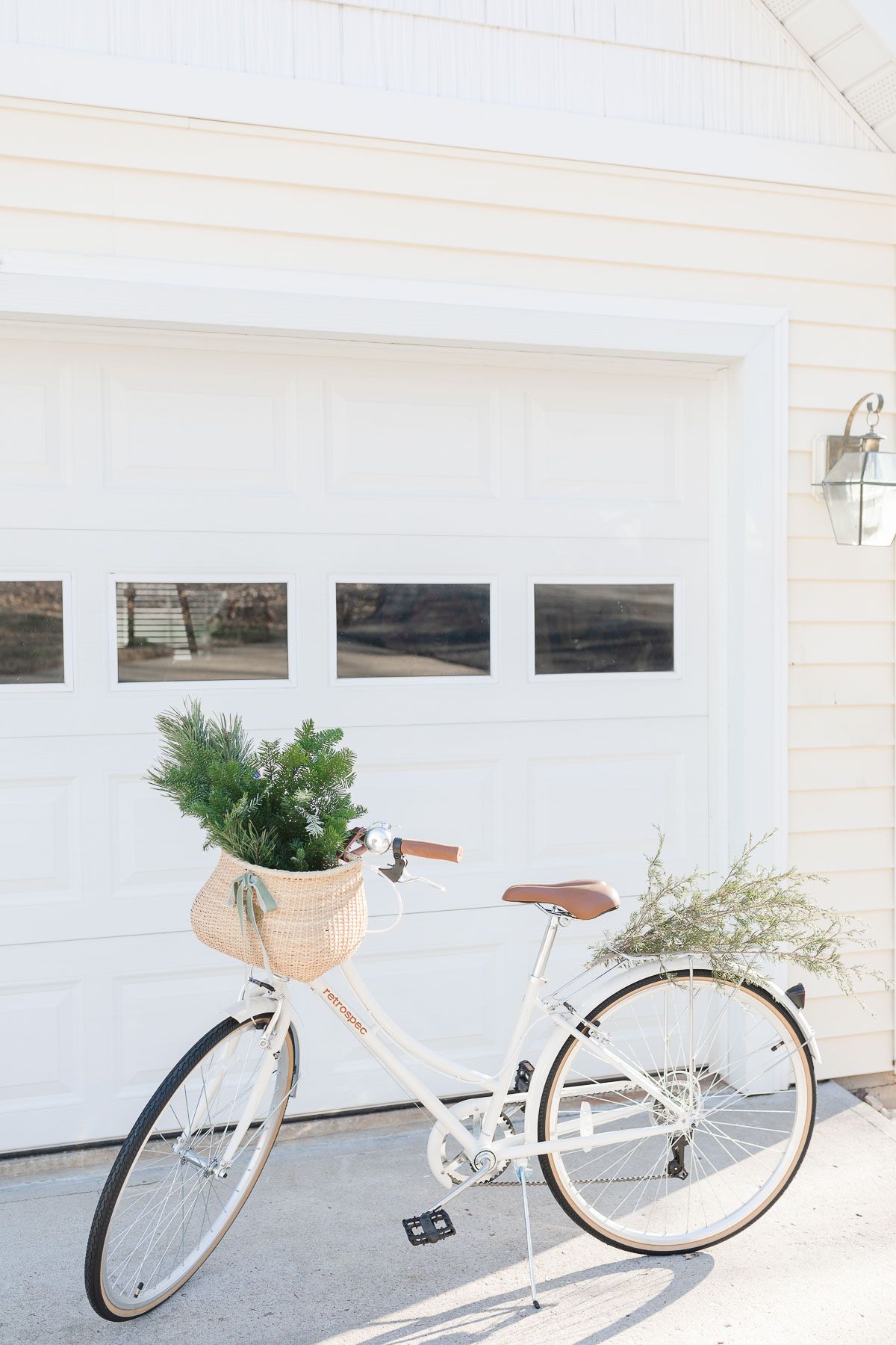 A white beach cruiser bike with Christmas greenery in the basket.