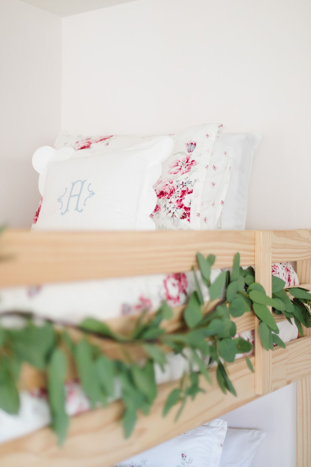 A bedroom with wooden bunk beds and floral bedding, decorated with garland for a coastal Christmas look.