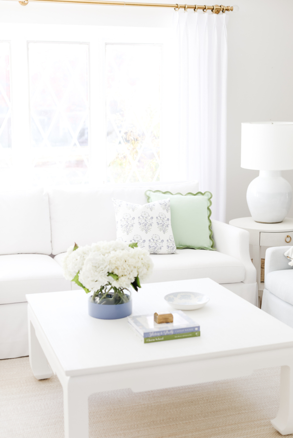 A decluttered living room with a white couch and a white coffee table.