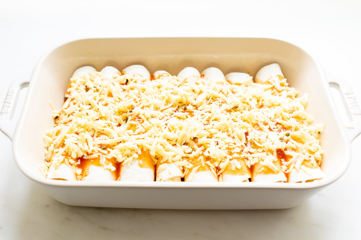 Cheese enchilada recipe in a white baking dish before baking.