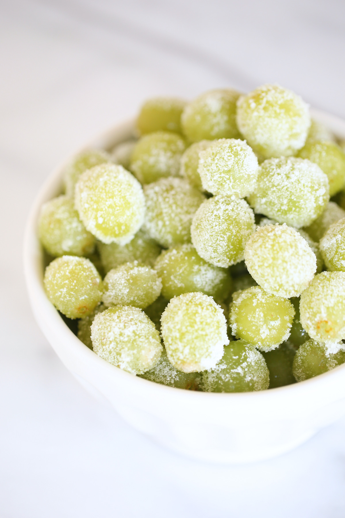 A white bowl of sugared prosecco grapes for a New Year's Eve Menu