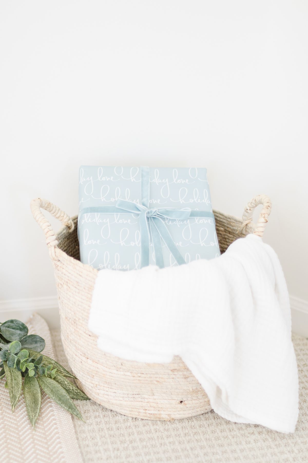 A basket with a blanket and a small blue package inside. 