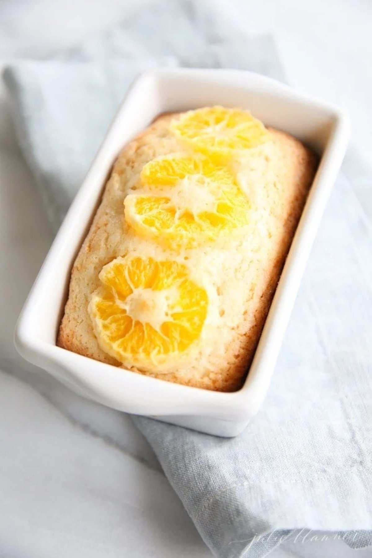 Sweet orange quick bread in a white loaf pan.