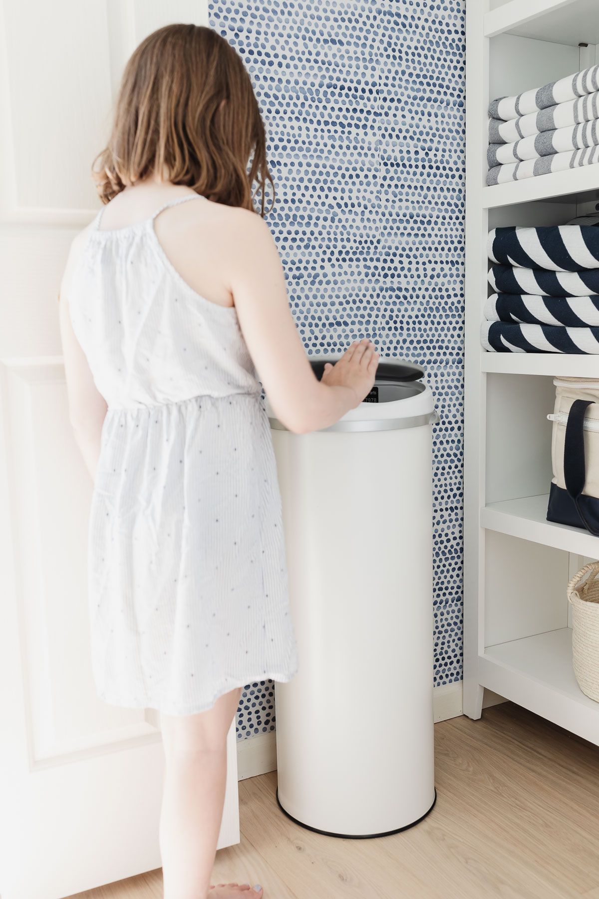 girl waving hand at trash can to open