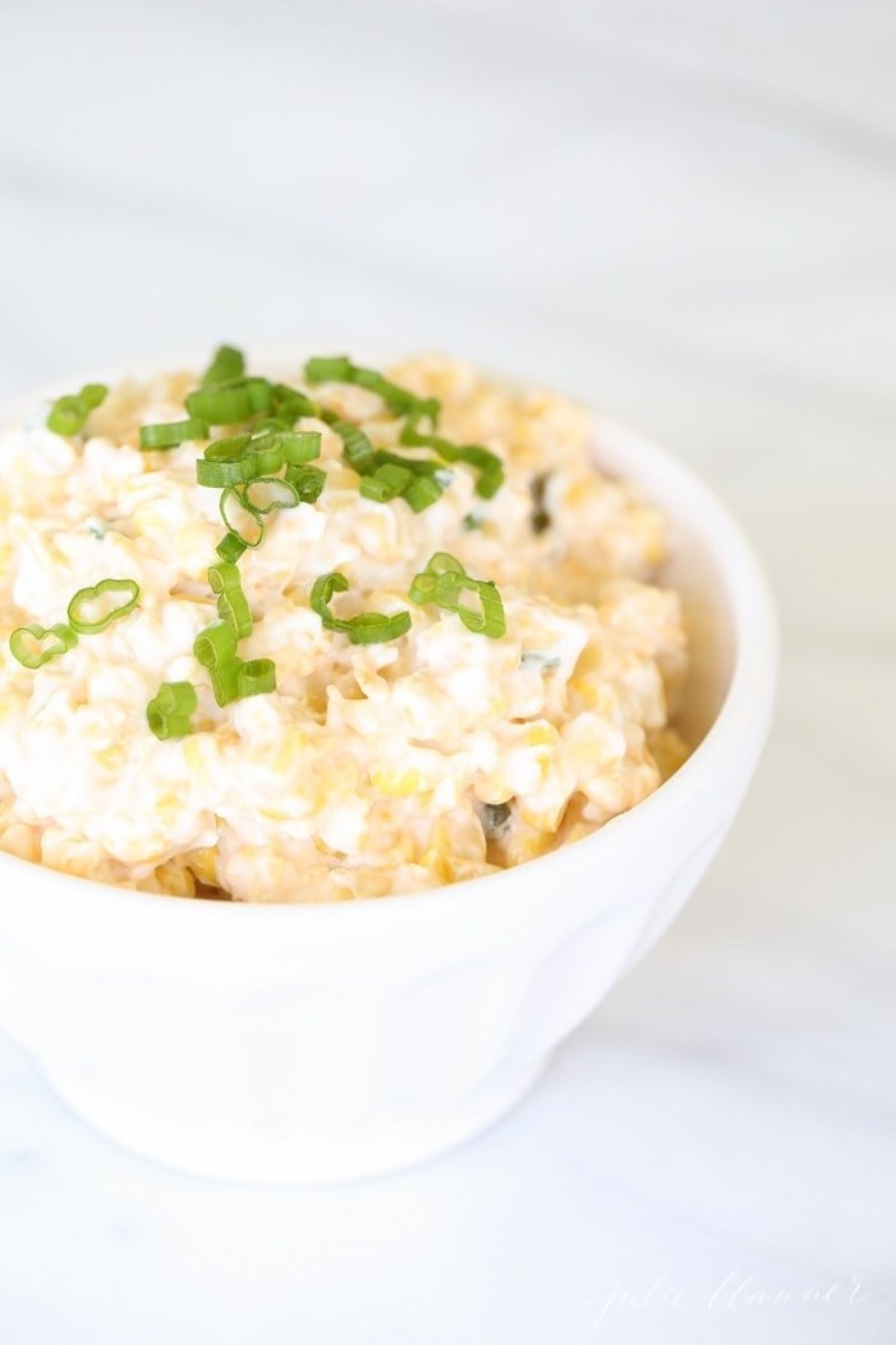 A white bowl full of cheesy corn dip. 