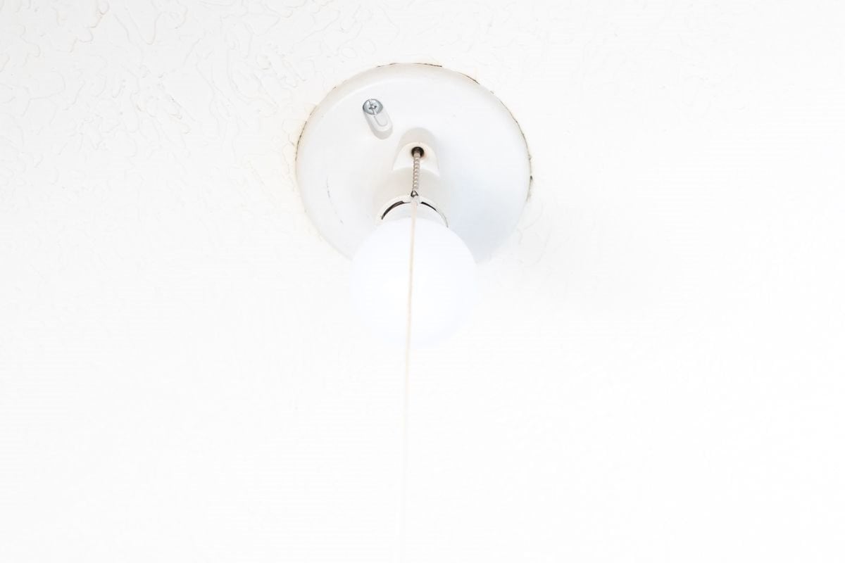 Pull chain light fixture on white ceiling. 