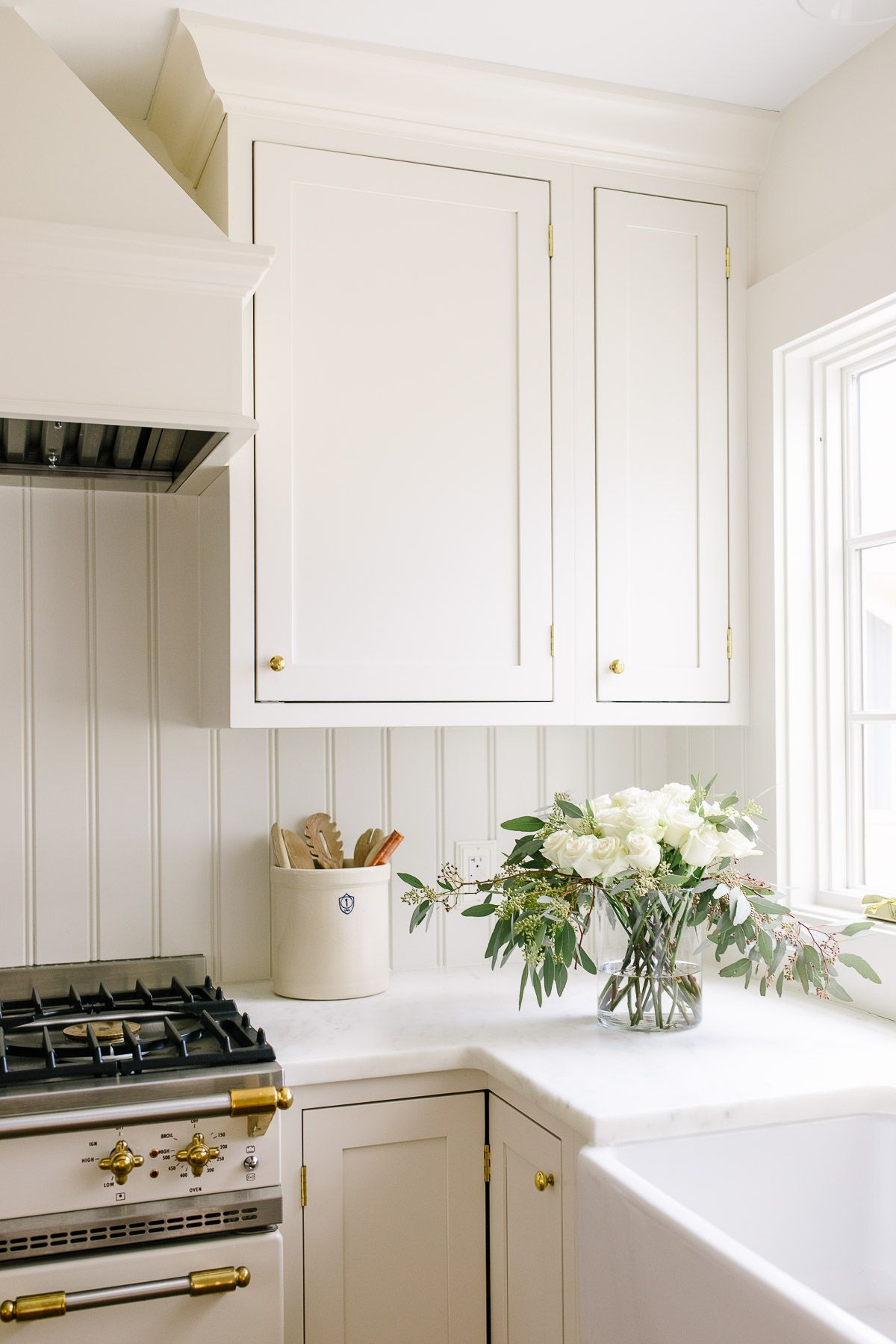 A cream kitchen with cabinets, walls and trim painted the same color. 