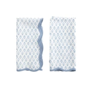 Two blue and white napkins with scalloped decor on a white background.