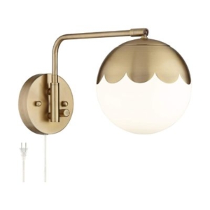 A brass wall light with a scalloped decor and a white ball on it.