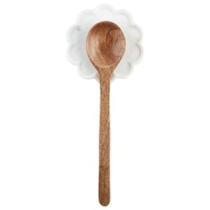 A wooden spoon with scalloped decor and a flower on it.