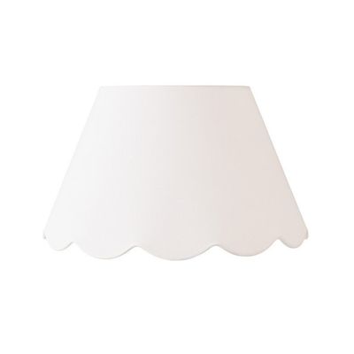 A white lamp shade with scalloped decor edges.